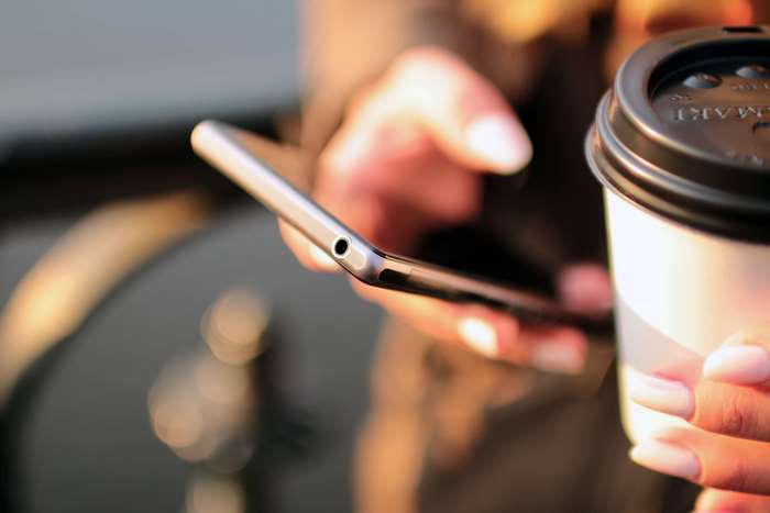 Person holding smartphone and coffee cup
