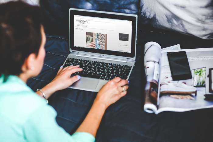 Woman working on Acer laptop with magazine and phone