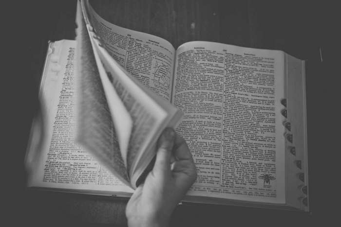 Black and white image of a hand flipping through a dictionary