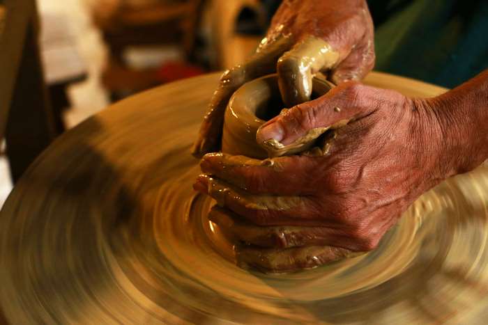 Hands shaping clay on a pottery wheel