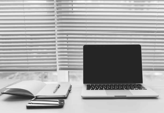 MacBook, notebook, pen, and smartphone on a desk