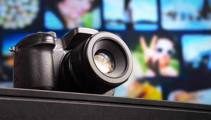 Black DSLR camera with lens on blurred background