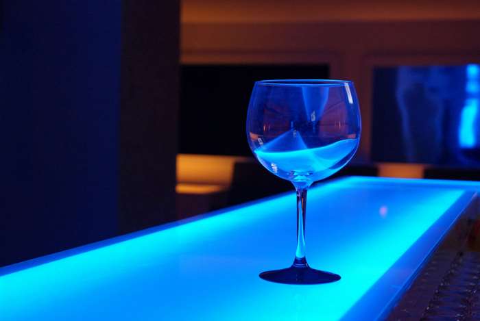 Wine glass on a blue illuminated bar counter