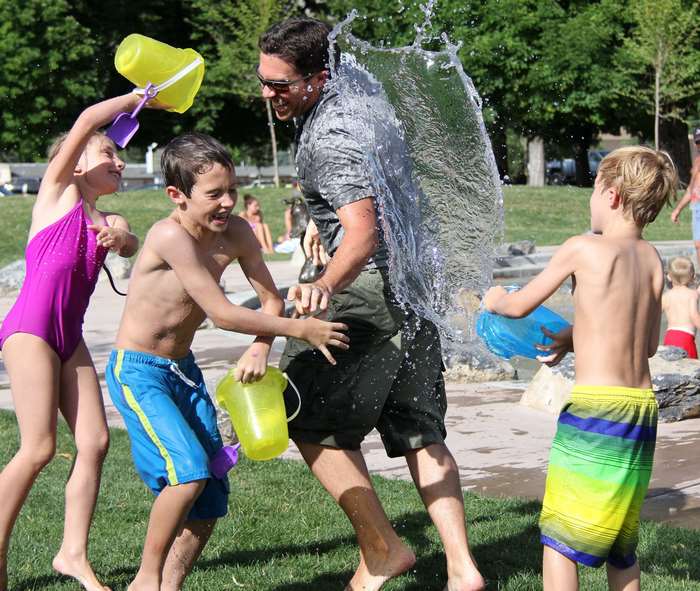 Man and children having a water fight outdoors