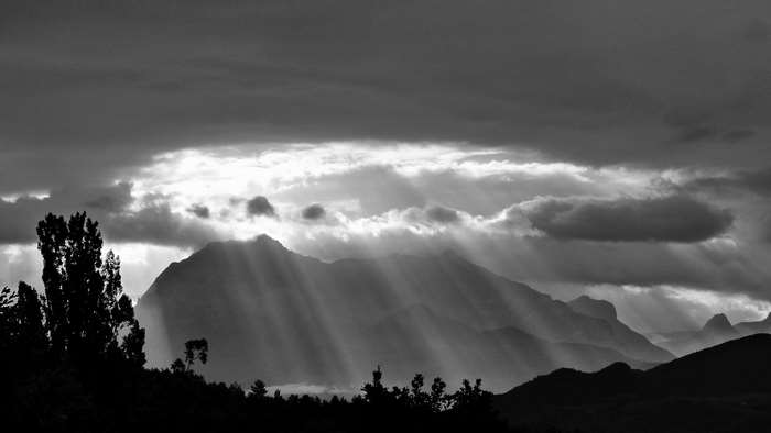 Sun rays breaking through clouds over mountains