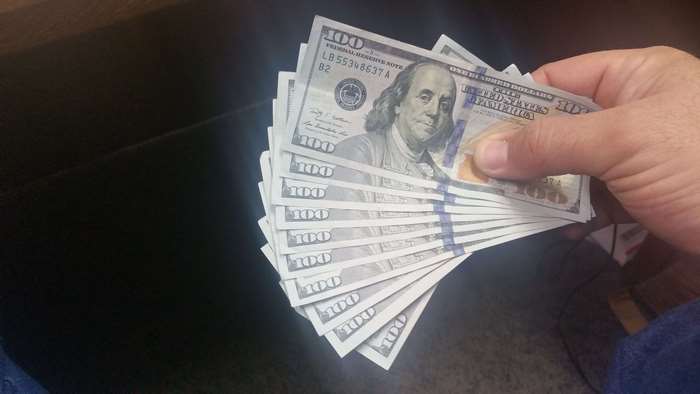 Hand holding fan of 100 dollar bills