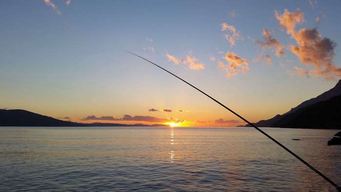 Fishing rod over a lake at sunset