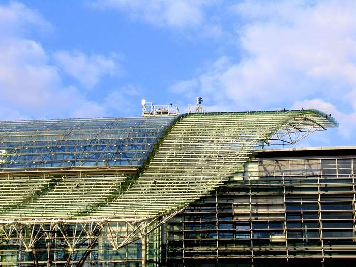 Glass roof structure of a modern building under a cloudy sky