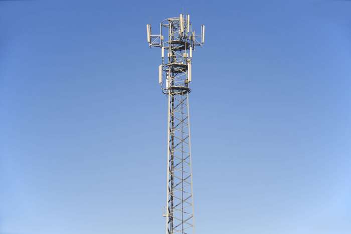 Cell tower with antennas against a clear blue sky
