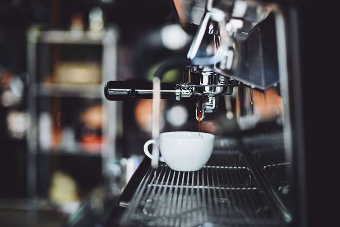 Espresso being brewed into a white cup from a coffee machine