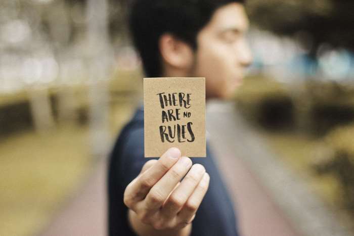 Man holding a card with "THERE ARE NO RULES" text