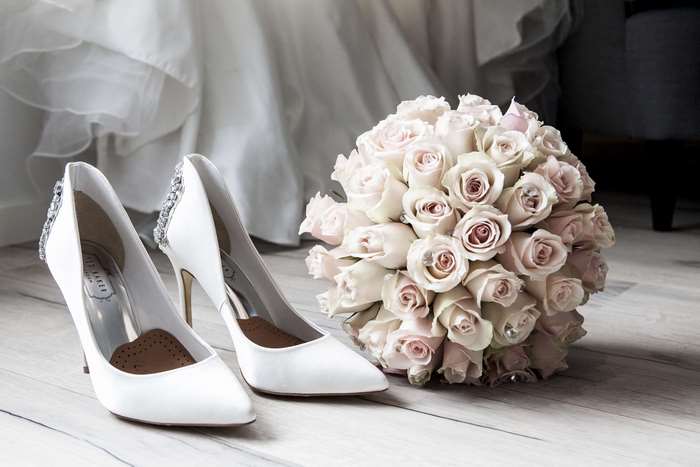White wedding shoes and pink roses bouquet