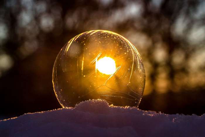 Sun shining through a frozen soap bubble on snow