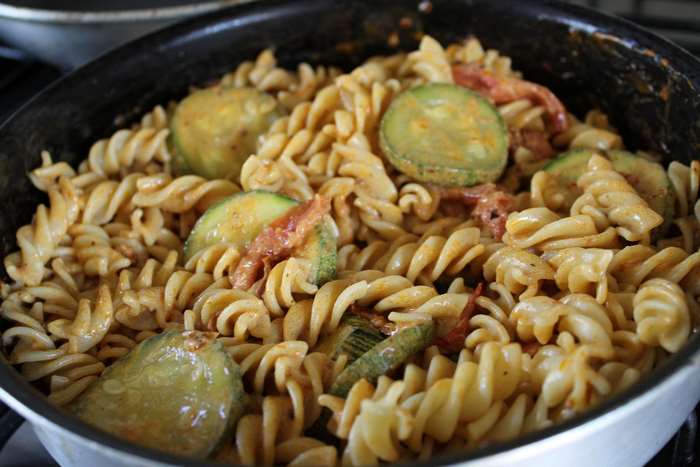 Creamy pasta with zucchini and sun-dried tomatoes in a pan
