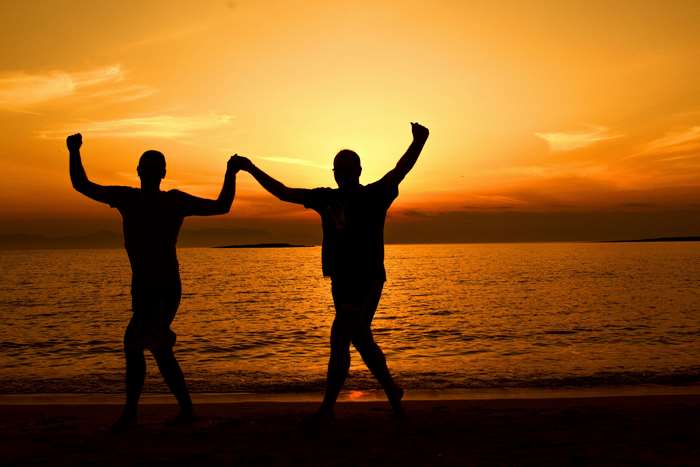 Two people dancing on a beach at sunset
