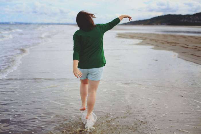 Woman walking barefoot on a beach in the water