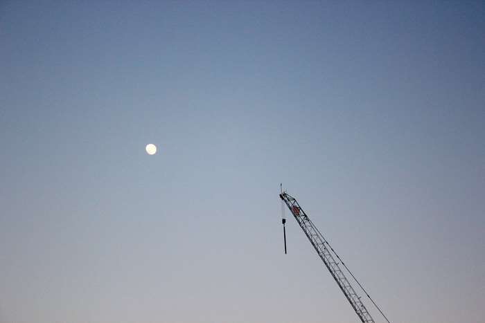 Minimalist crane and full moon in clear sky