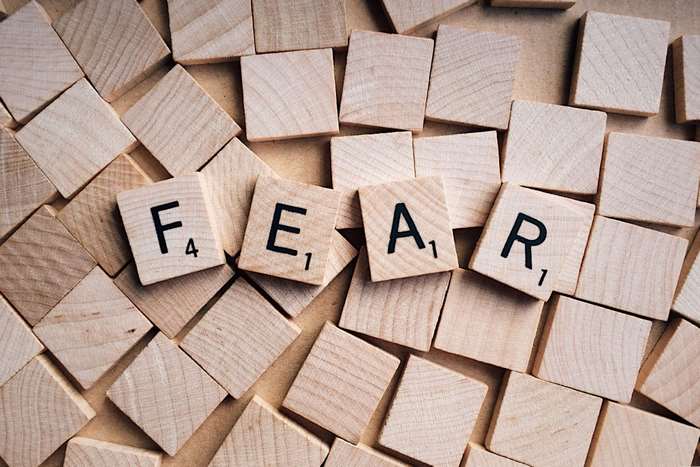 Scrabble tiles spelling FEAR on wooden background