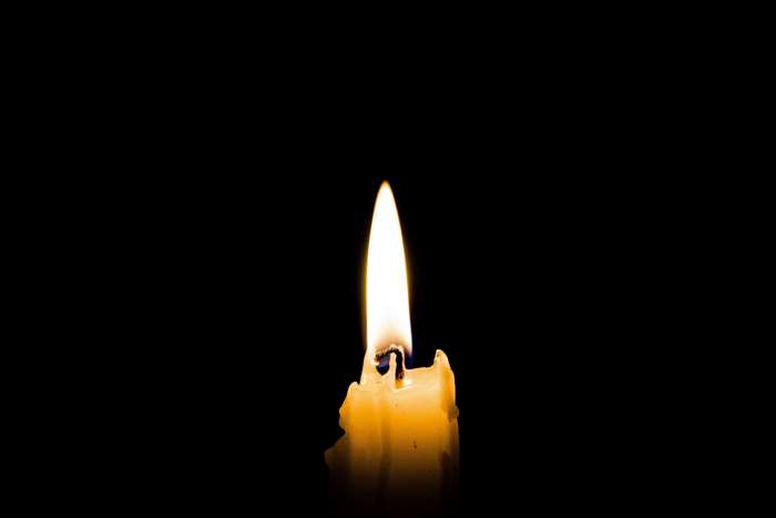 Close-up of a lit yellow candle in the dark