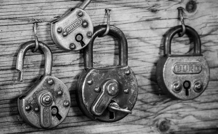 Three padlocks hanging on a wooden wall