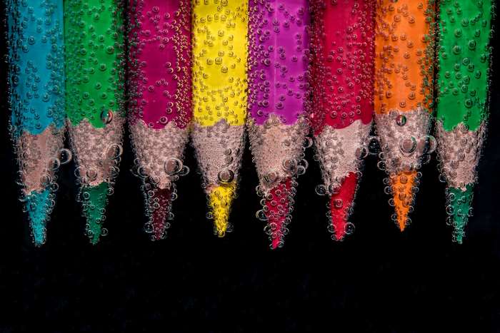 Colored pencils submerged in water with air bubbles
