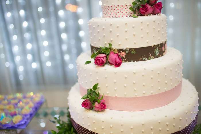 Multi-tiered white cake with pink roses and floral ribbon