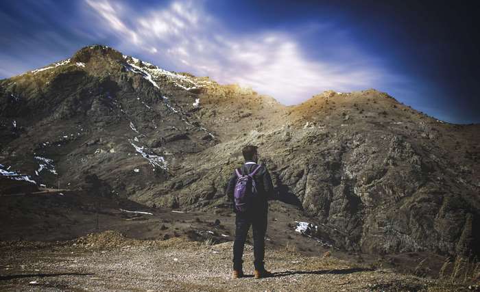 Man with backpack looking at a mountain landscape