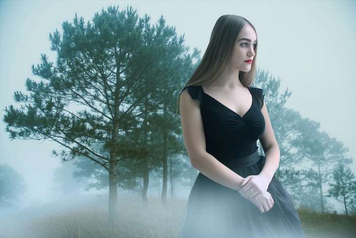 Woman in black dress in foggy forest