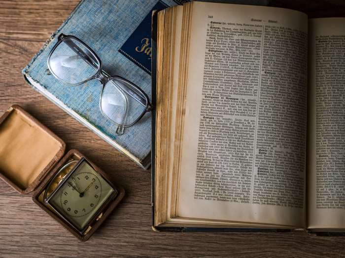 Antique book, glasses, and pocket watch on wooden table