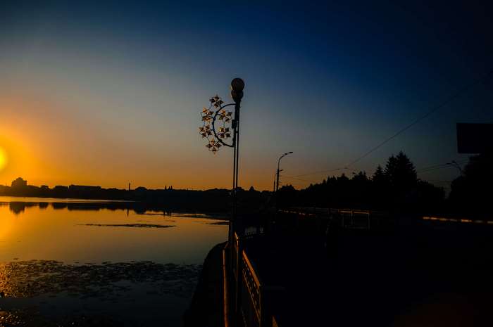 Sunset over a lake with a decorative lamppost