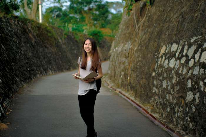 Woman holding a book on a road between rock walls