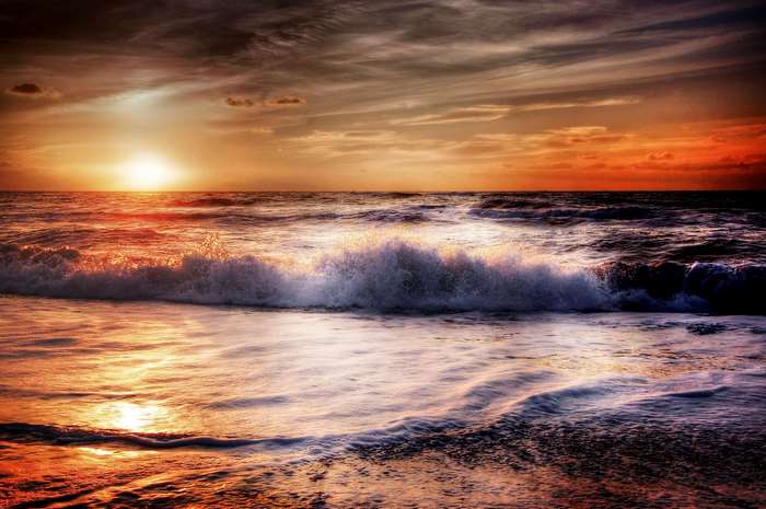 Sunset over the ocean with crashing waves