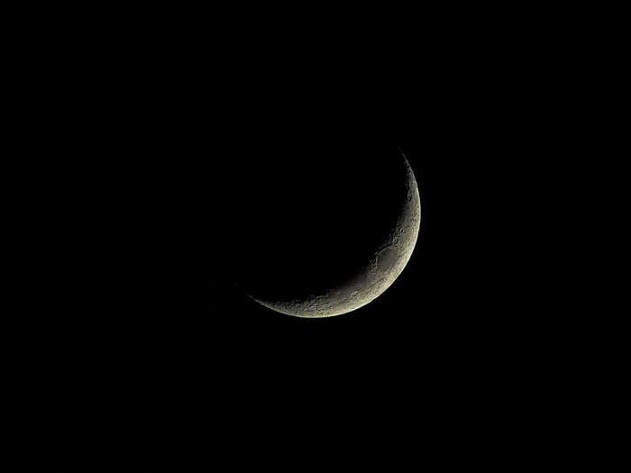 Crescent moon with craters in dark space