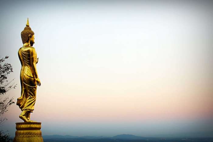 Golden Buddha statue overlooking a landscape at sunset