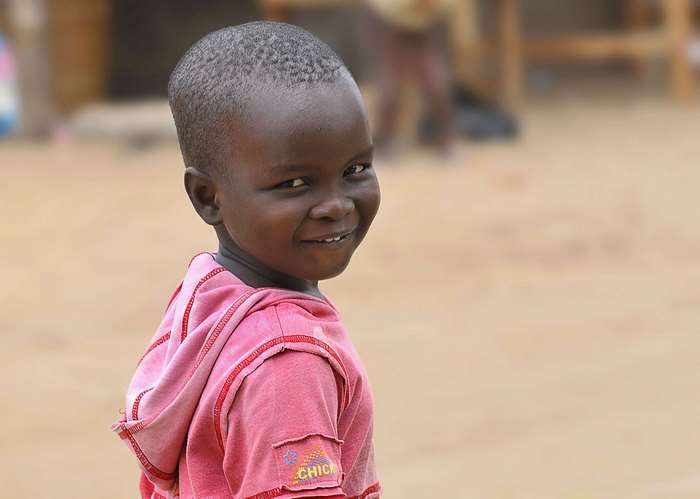Young African child smiling in a pink hoodie