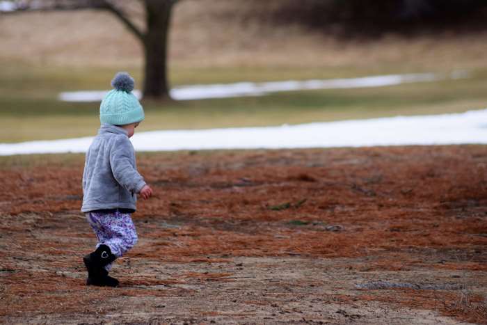 Toddler walking in a park with snow patches