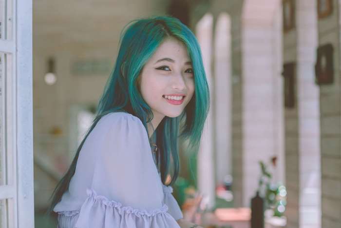 Young woman with teal hair smiling
