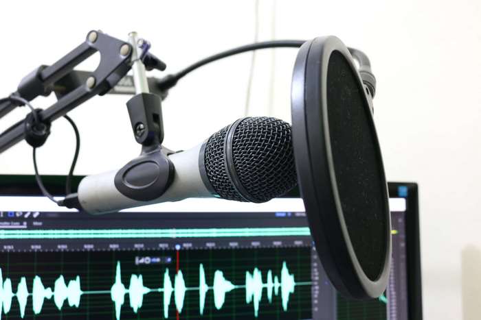 Microphone with pop filter and audio waveform on monitor
