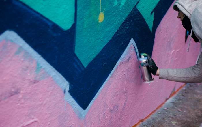 Person spraying graffiti on a colorful wall