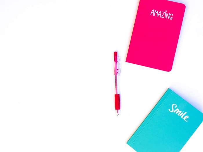 Pink and turquoise notebooks with a pen