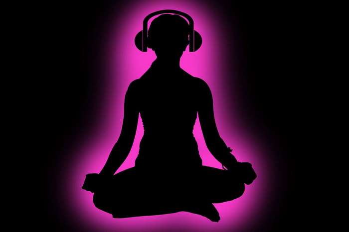 Silhouette of person meditating with headphones and pink aura