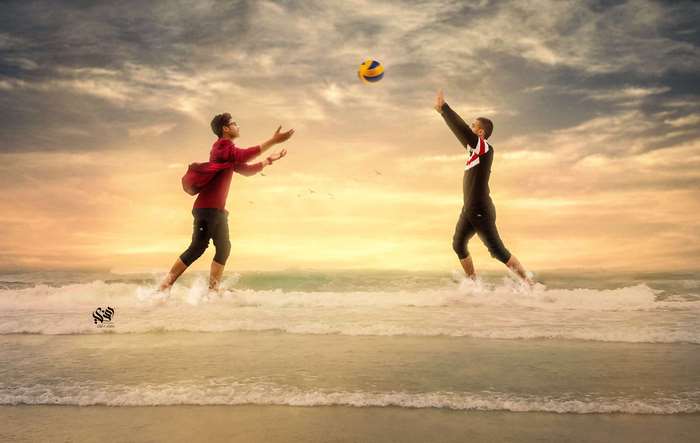Two men playing volleyball on a beach at sunset