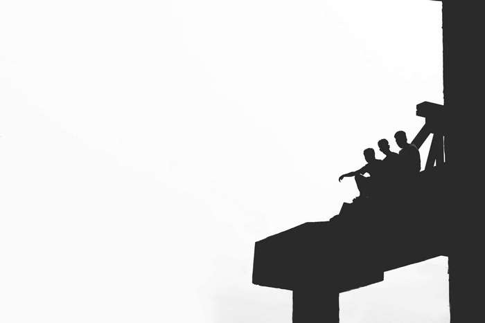 Silhouettes of friends sitting on a structure