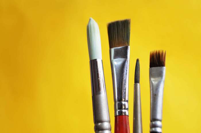 Paint brushes on a yellow background