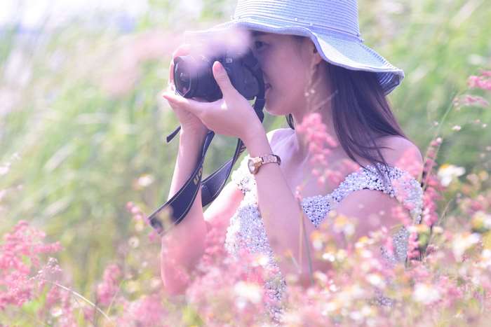 Woman in a hat taking a photo in a field of flowers
