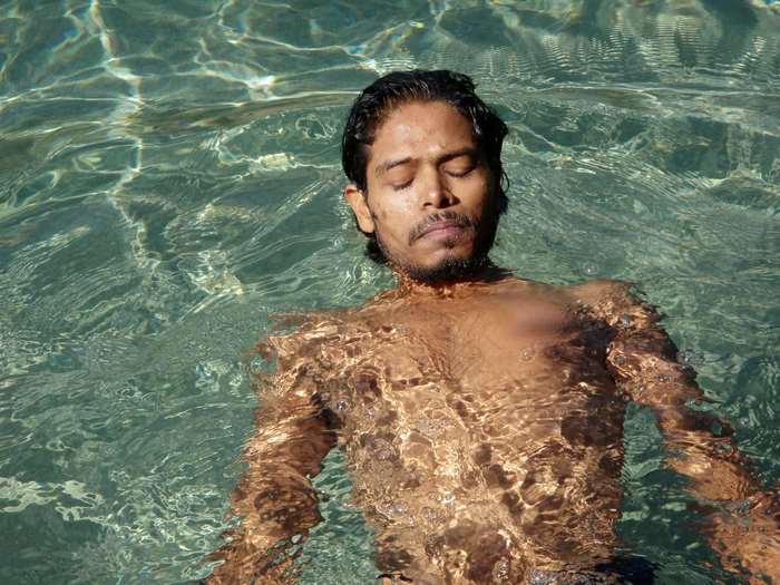 Man floating in clear water with eyes closed
