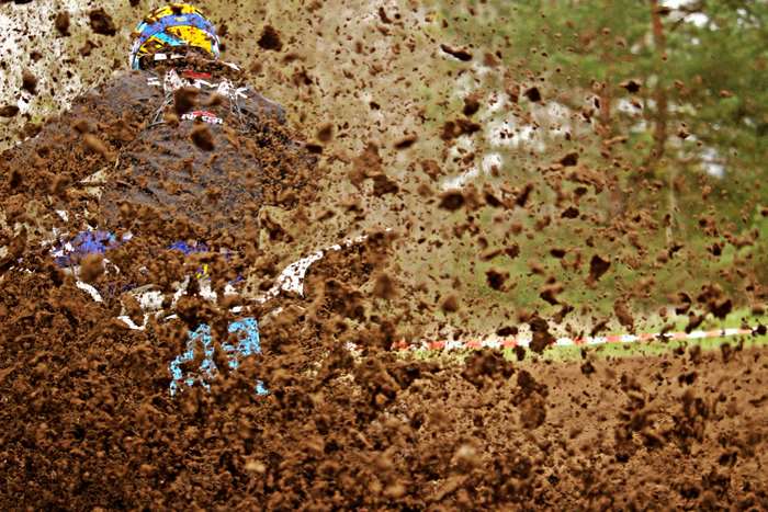 Motocross rider splashing through mud