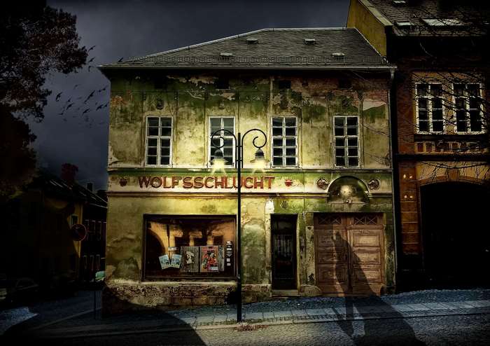 Creepy old building with 'WOLFSSCHLUCHT' sign at night
