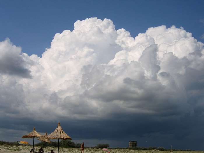 Beach with large rain clouds and umbrellas