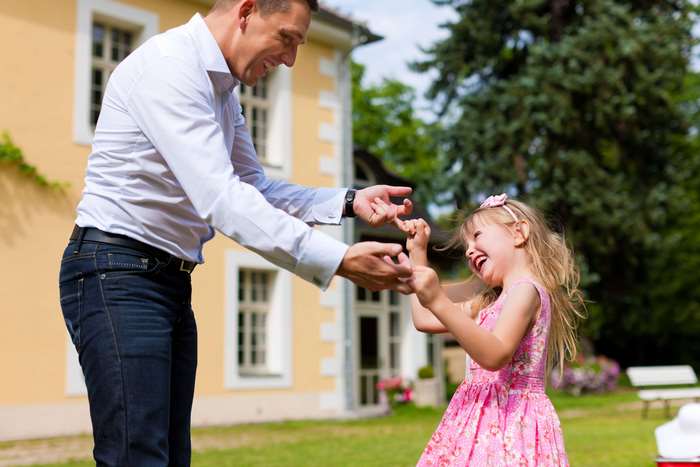 Father and daughter dancing in a garden